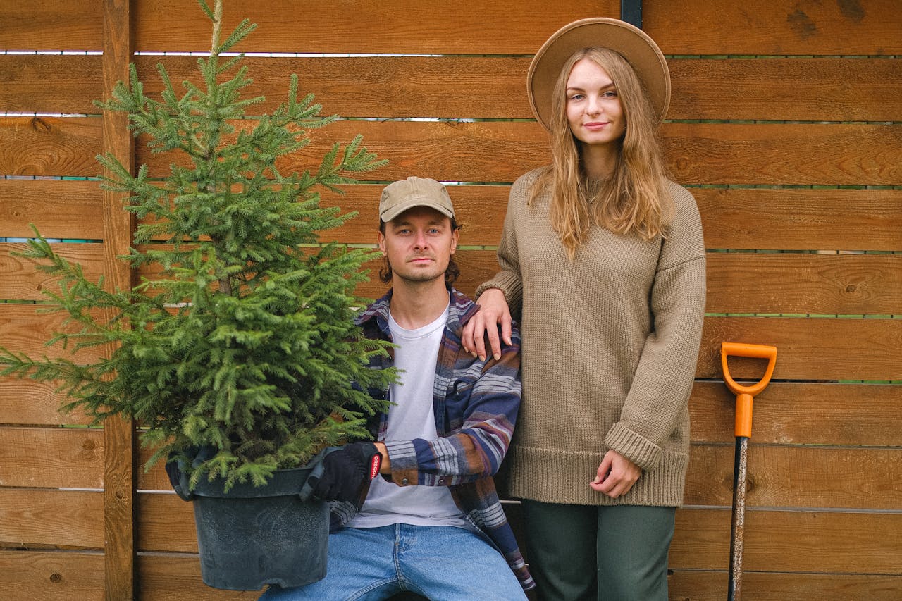 A young couple gardening together with an evergreen plant, showcasing teamwork and nature care.